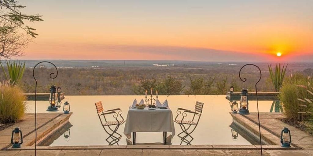 luxury safari lodge - stanley safari lodge, pool and set table at sunset